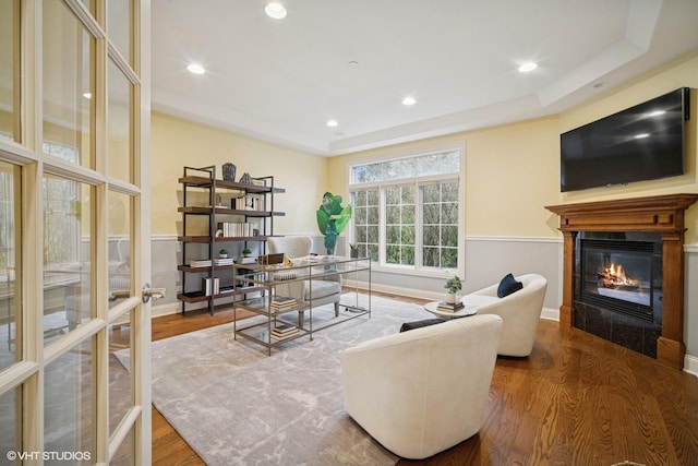 living area with a glass covered fireplace, baseboards, and wood finished floors