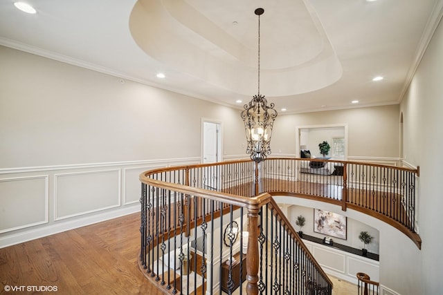 stairs with crown molding, wainscoting, wood finished floors, recessed lighting, and a chandelier