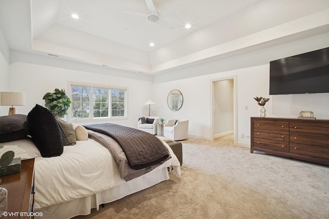 bedroom with a tray ceiling, recessed lighting, and light colored carpet