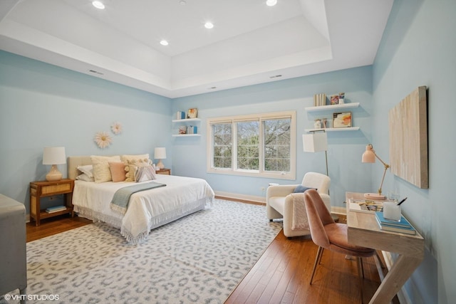 bedroom featuring recessed lighting, a raised ceiling, baseboards, and hardwood / wood-style floors