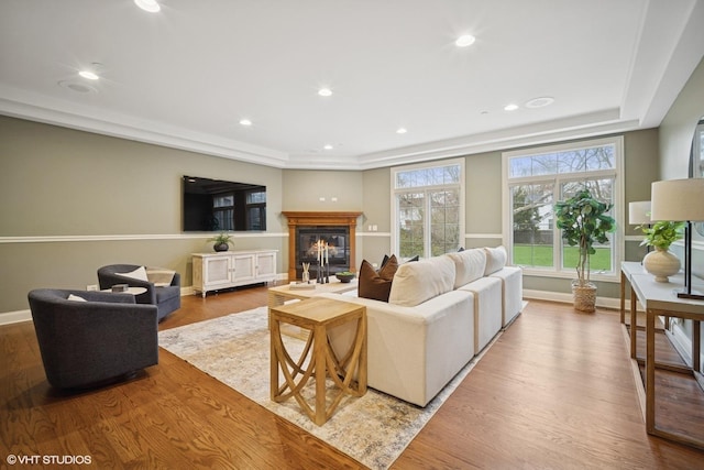 living area featuring recessed lighting, baseboards, a glass covered fireplace, and wood finished floors