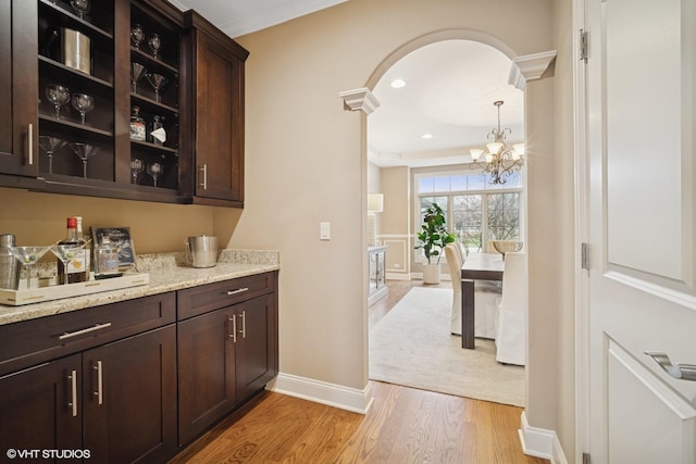 bar with hanging light fixtures, a chandelier, light wood-style flooring, recessed lighting, and baseboards