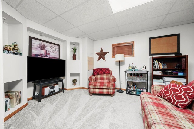 living area with carpet floors, baseboards, and a drop ceiling