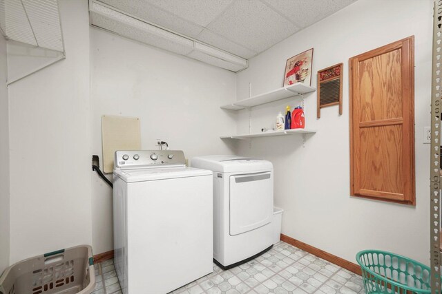 laundry area with baseboards, laundry area, light floors, and washer and dryer