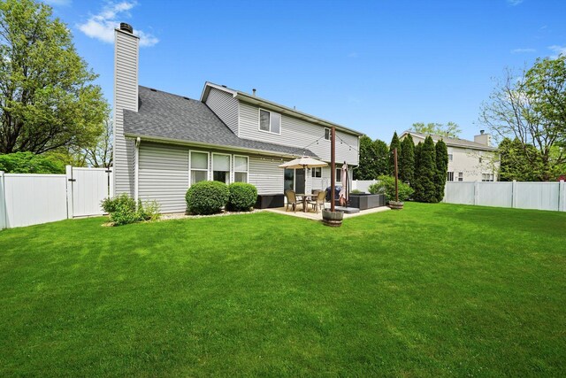 rear view of property featuring a lawn, a patio, and a fenced backyard