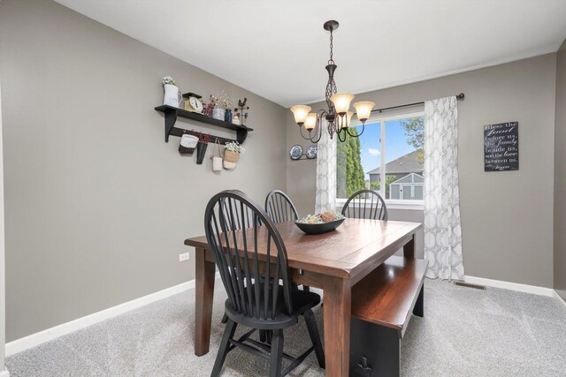 carpeted dining area with baseboards and a chandelier