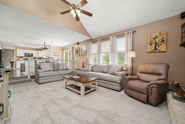carpeted living room featuring vaulted ceiling and ceiling fan with notable chandelier