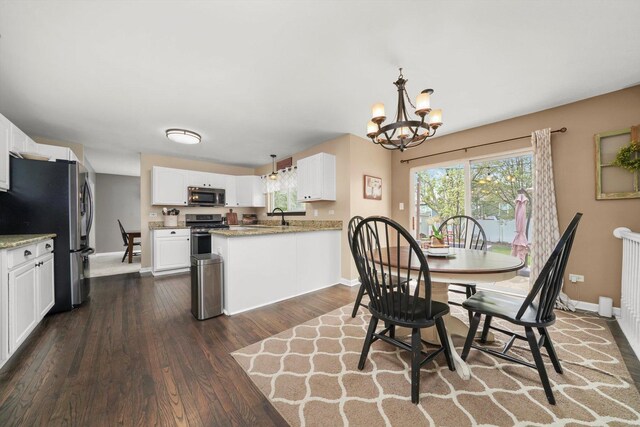 dining room with baseboards, a notable chandelier, a healthy amount of sunlight, and dark wood-type flooring