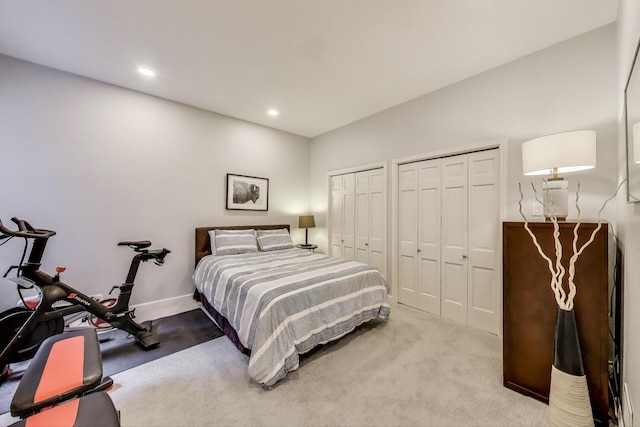 carpeted bedroom featuring recessed lighting, baseboards, and two closets