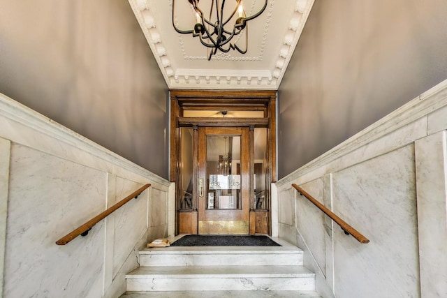 staircase featuring a wainscoted wall and a notable chandelier