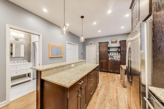 kitchen featuring freestanding refrigerator, pendant lighting, a kitchen island, and light wood-type flooring