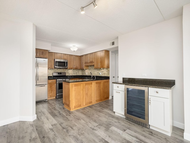 kitchen featuring visible vents, appliances with stainless steel finishes, tasteful backsplash, light wood-type flooring, and wine cooler
