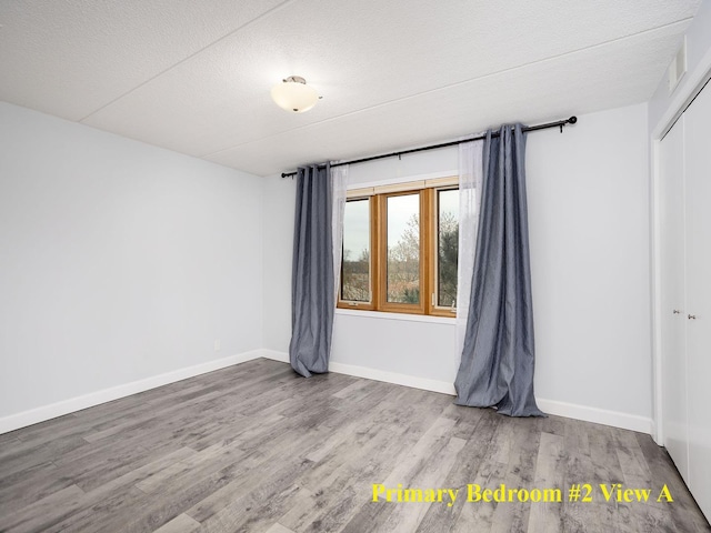 unfurnished room featuring baseboards, a textured ceiling, and wood finished floors