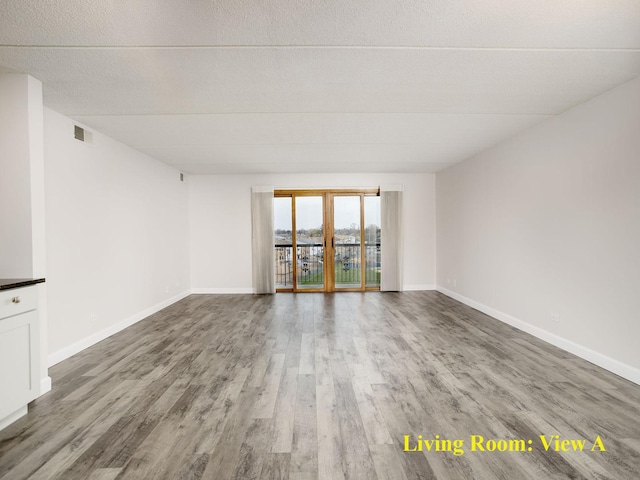 spare room with visible vents, baseboards, and wood finished floors