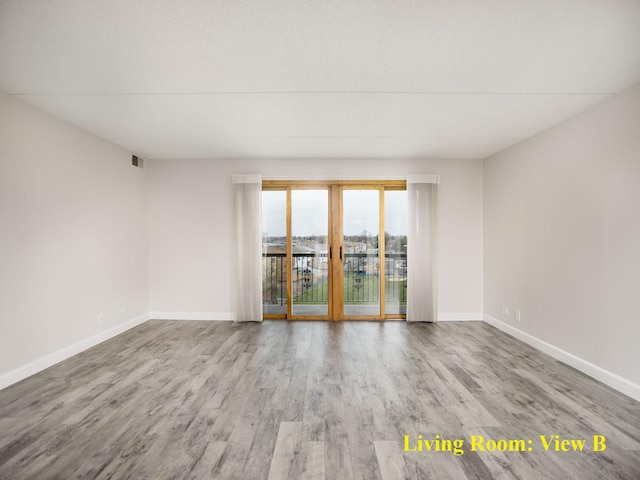 spare room featuring baseboards, visible vents, and wood finished floors