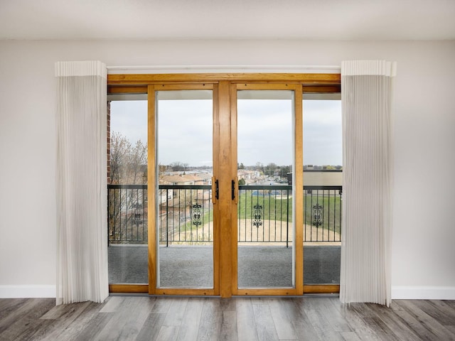 doorway to outside featuring baseboards and wood finished floors