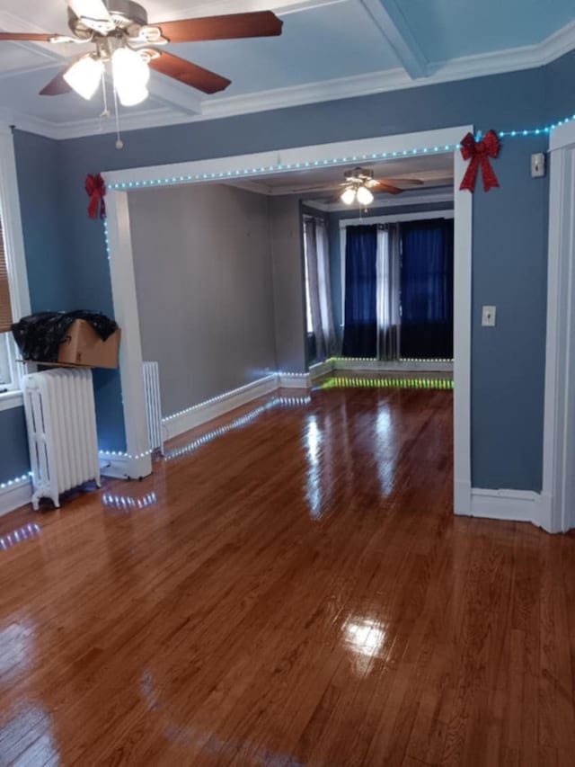 spare room featuring radiator heating unit, baseboards, a ceiling fan, and wood finished floors