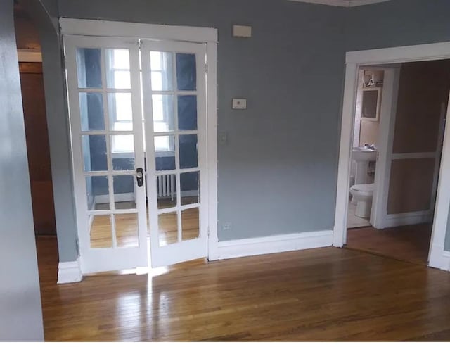 doorway to outside with arched walkways, baseboards, french doors, and wood finished floors