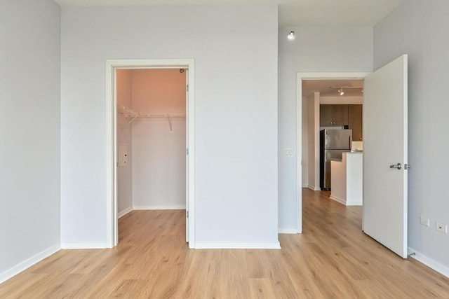 125 S Green St Unit 1007A, Chicago, IL 60607 - unfurnished bedroom with freestanding refrigerator, light wood-style floors, a walk in closet, baseboards, and a closet