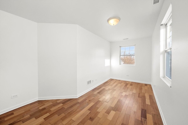 spare room with baseboards, visible vents, and light wood finished floors