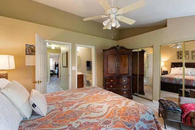 bedroom with light colored carpet, connected bathroom, ceiling fan, and two closets