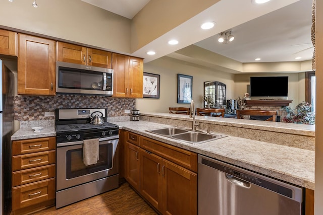 kitchen with a sink, light countertops, brown cabinetry, stainless steel appliances, and decorative backsplash