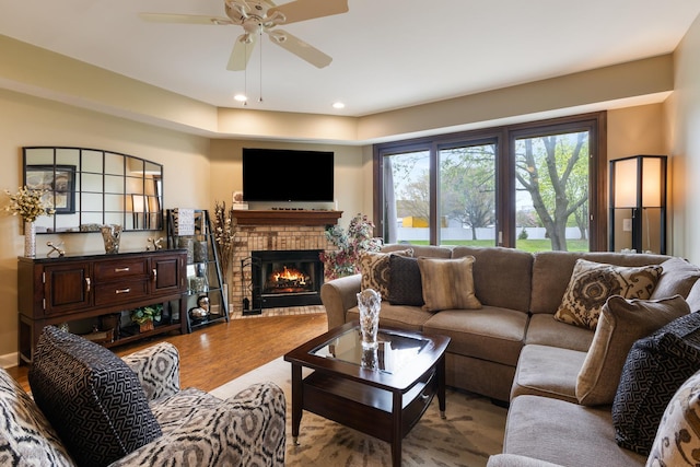 living area featuring a brick fireplace, recessed lighting, ceiling fan, and wood finished floors
