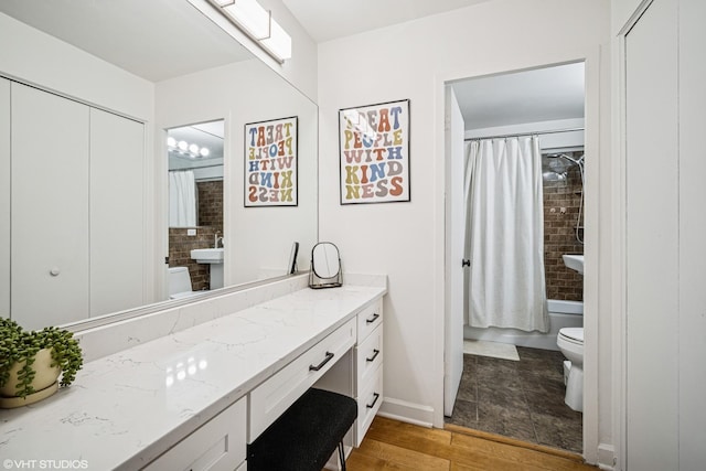 bathroom featuring shower / bath combination with curtain, wood finished floors, vanity, baseboards, and toilet