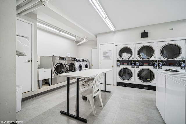 community laundry room featuring light tile patterned floors, stacked washer and clothes dryer, and washing machine and clothes dryer
