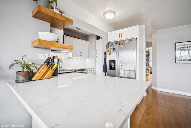 kitchen featuring appliances with stainless steel finishes, open shelves, light stone counters, a peninsula, and white cabinetry
