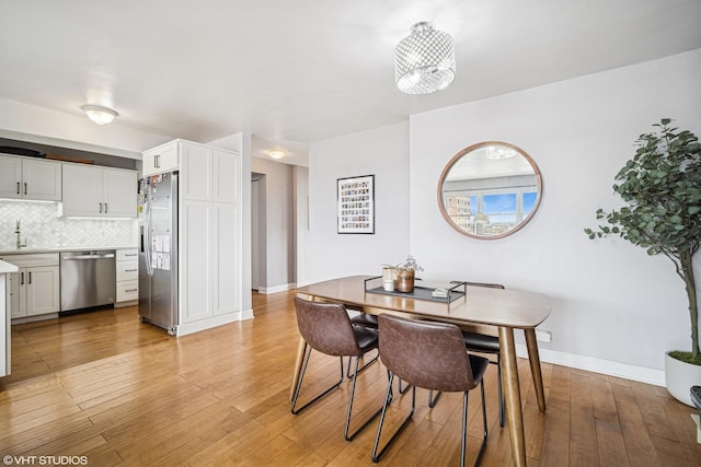 dining space with baseboards and light wood-style flooring