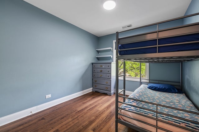 bedroom featuring baseboards, wood finished floors, and visible vents