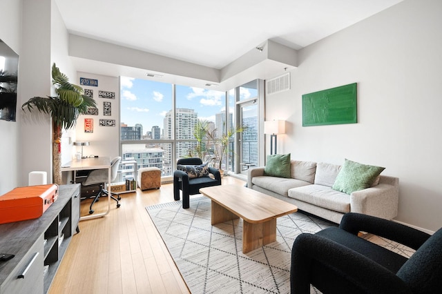 living area with light wood-type flooring, a city view, and visible vents