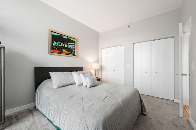 carpeted bedroom with baseboards and two closets