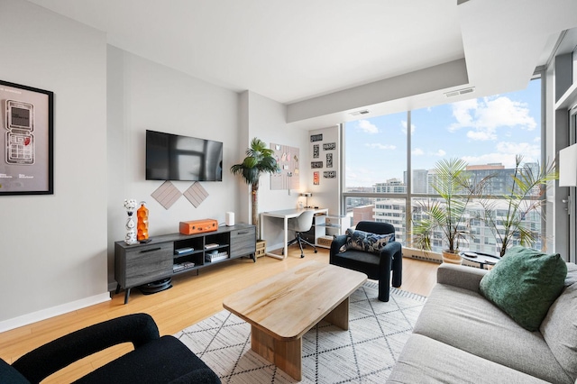 living area with visible vents, baseboards, wood finished floors, and a wall of windows