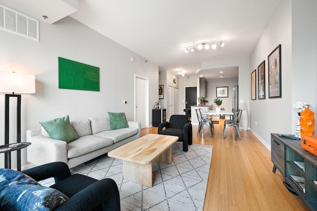 living area with baseboards, light wood-style flooring, and visible vents