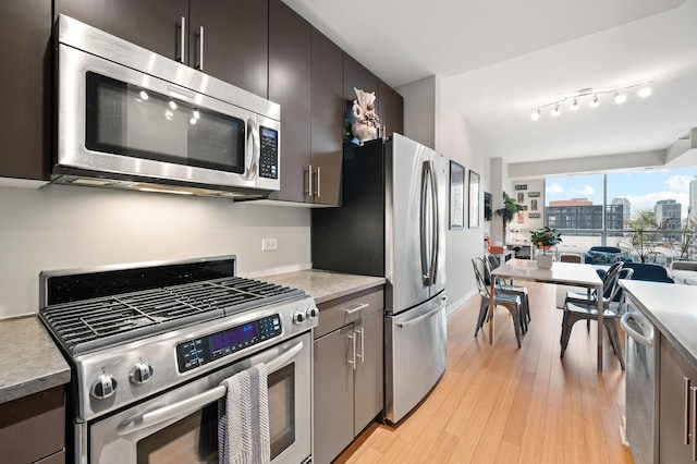 kitchen with light countertops, stainless steel appliances, open floor plan, light wood-type flooring, and a city view