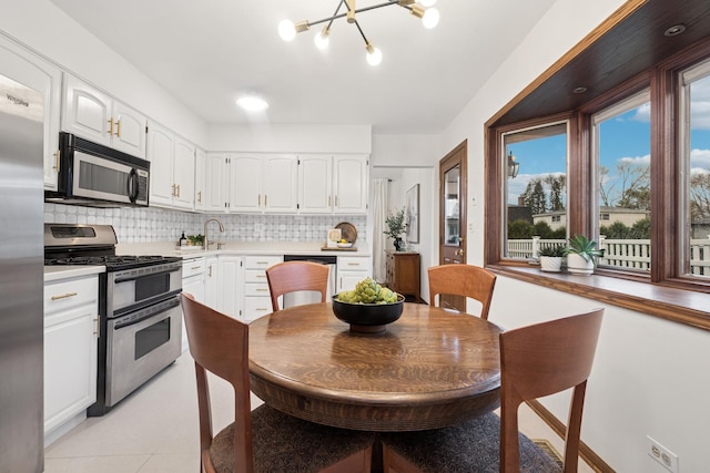 kitchen with light countertops, white cabinetry, a sink, appliances with stainless steel finishes, and backsplash