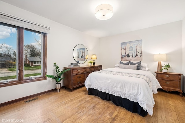 bedroom featuring visible vents, light wood-style floors, baseboards, and multiple windows