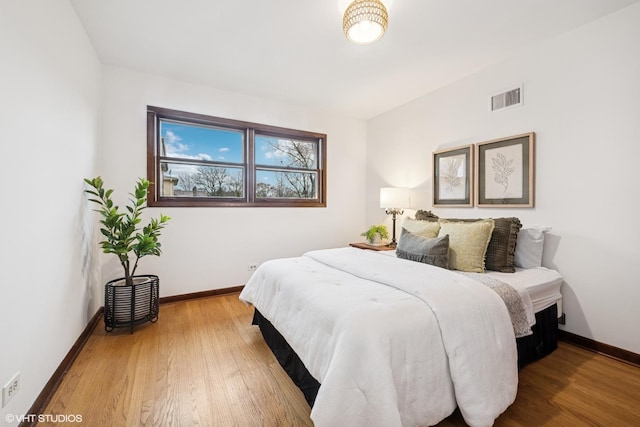 bedroom featuring baseboards, visible vents, and wood finished floors