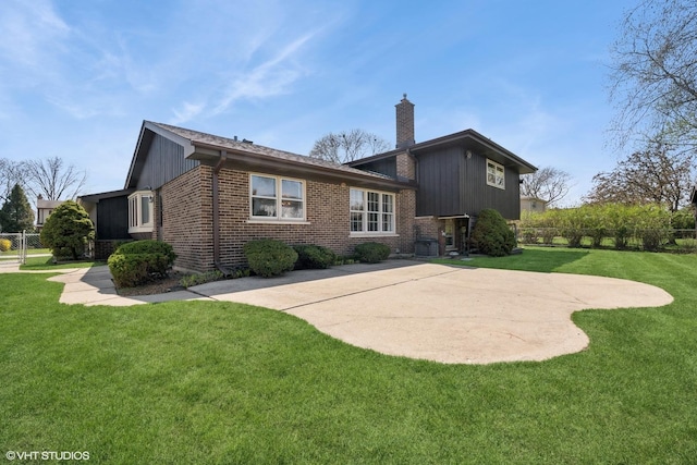 back of property with a lawn, brick siding, fence, and a chimney