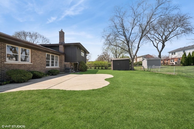 view of yard featuring a storage unit, an outdoor structure, a fenced backyard, and a patio
