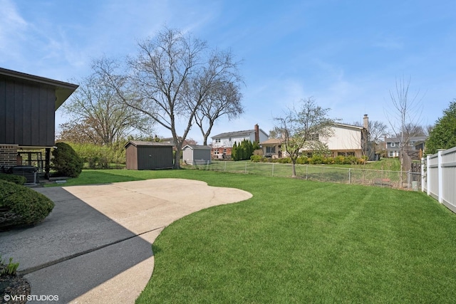 view of yard with a storage unit, a fenced backyard, a patio area, and an outbuilding