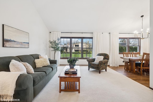 living room with vaulted ceiling, wood finished floors, and a notable chandelier