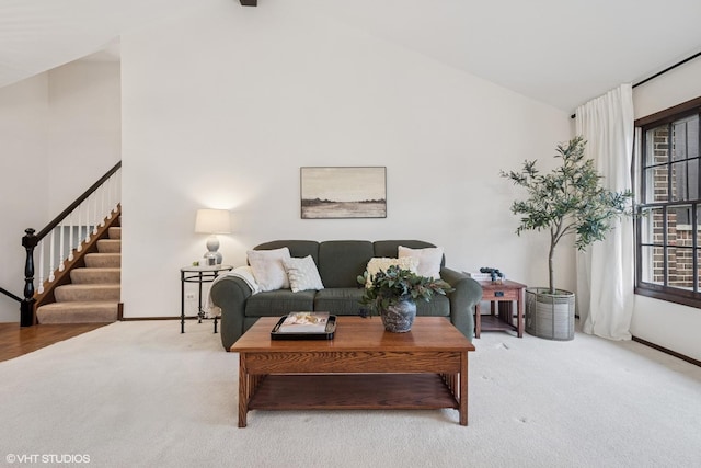 carpeted living area with baseboards, stairs, and vaulted ceiling