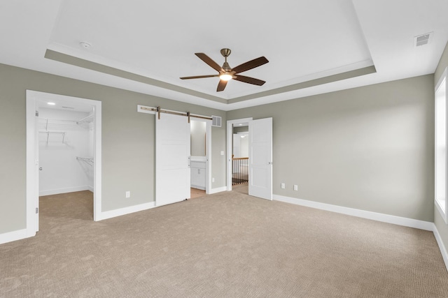 407 Sutton St, Savoy, IL 61874 - unfurnished bedroom featuring a raised ceiling, a walk in closet, light carpet, and a barn door