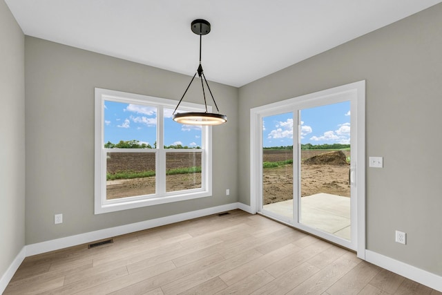 407 Sutton St, Savoy, IL 61874 - unfurnished dining area featuring baseboards and light wood-style floors