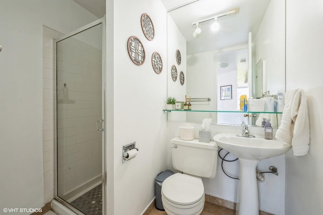 bathroom with track lighting, a stall shower, and toilet