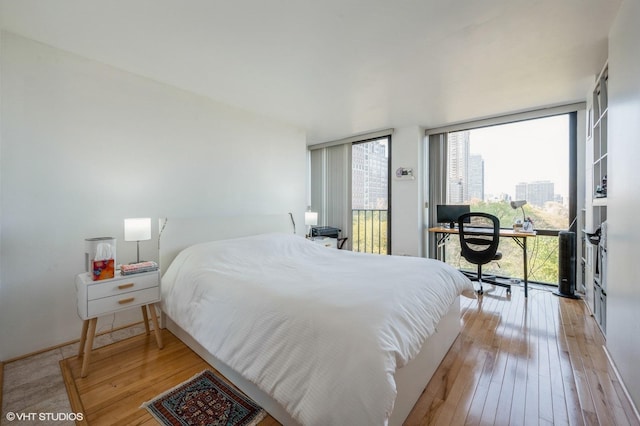 bedroom with access to exterior, expansive windows, and light wood-type flooring