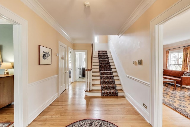 entryway featuring ornamental molding, light wood-style floors, stairs, and baseboards